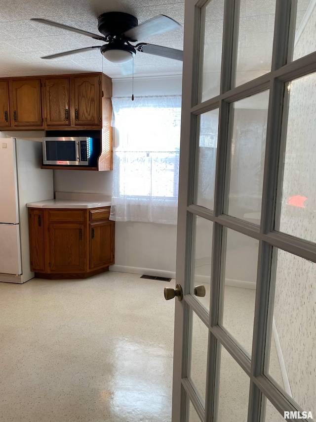 kitchen with ceiling fan, a textured ceiling, and white refrigerator