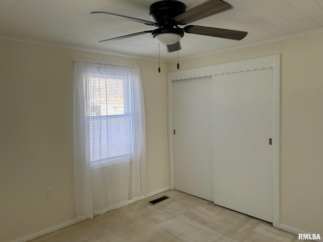 unfurnished bedroom featuring ceiling fan, light colored carpet, a closet, and ornamental molding