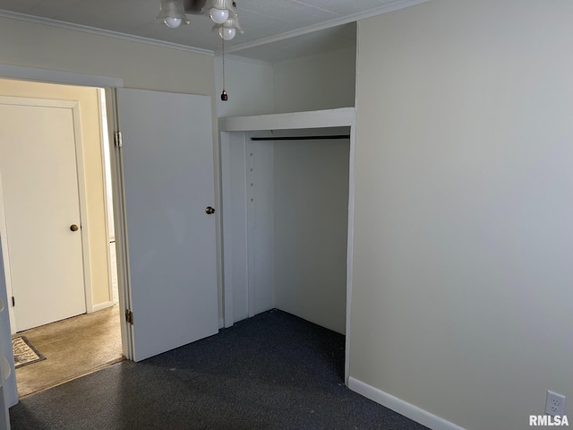 unfurnished bedroom featuring a closet, ornamental molding, and dark carpet