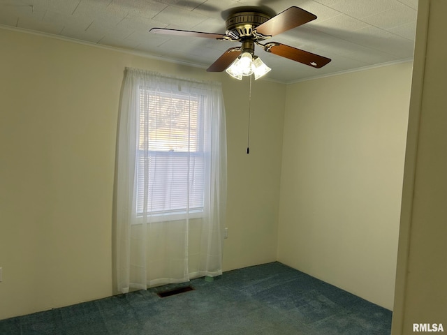 spare room with ceiling fan, ornamental molding, and dark carpet