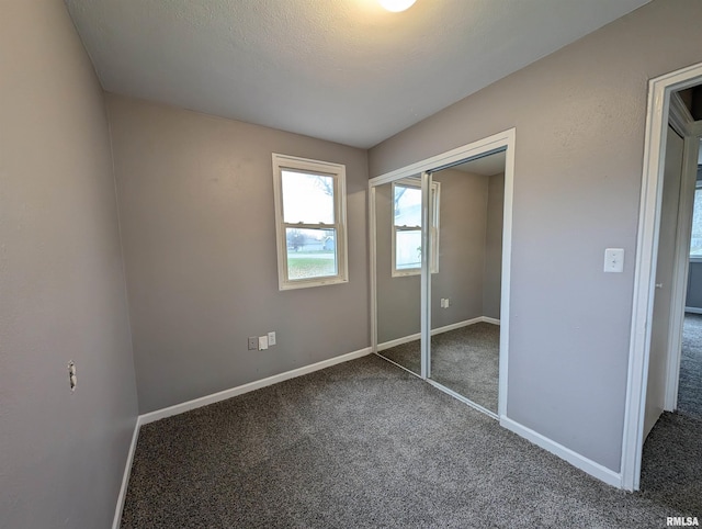 unfurnished bedroom with a textured ceiling, a closet, and dark colored carpet