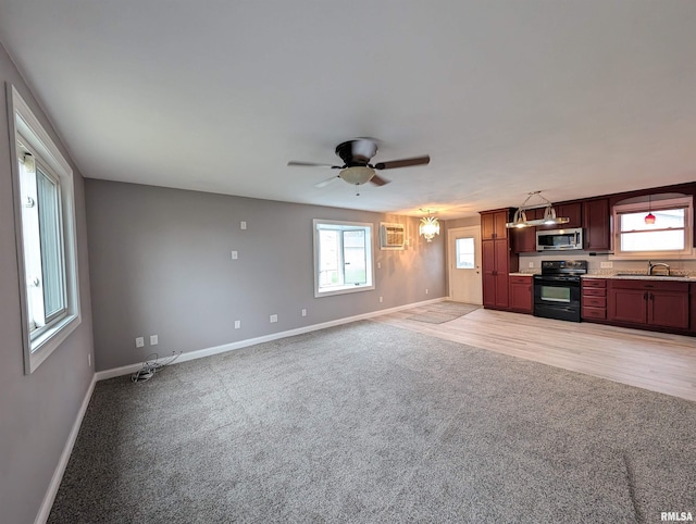 unfurnished living room with ceiling fan with notable chandelier, sink, an AC wall unit, and light carpet