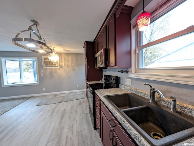 kitchen with black range with electric cooktop, a chandelier, pendant lighting, light hardwood / wood-style flooring, and sink