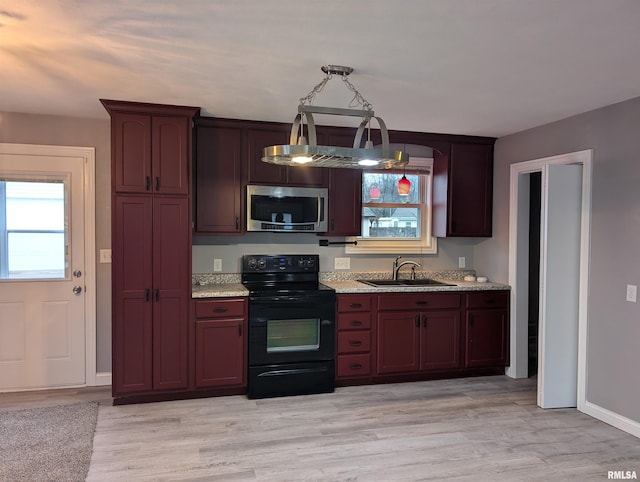 kitchen featuring black range with electric cooktop, pendant lighting, light wood-type flooring, and sink