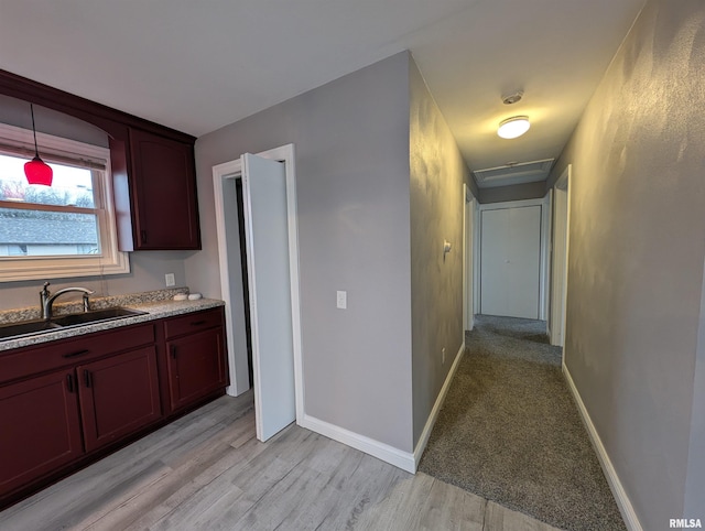 kitchen featuring sink, hanging light fixtures, and light hardwood / wood-style flooring