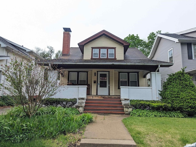 bungalow-style home with a chimney, a porch, and a front yard