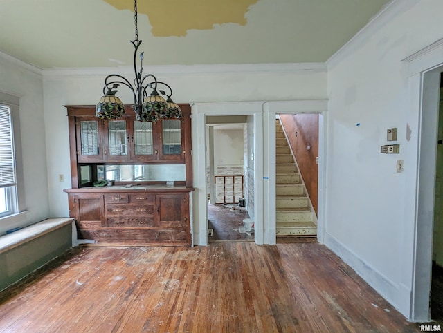 unfurnished dining area featuring dark wood-type flooring, a chandelier, crown molding, and a healthy amount of sunlight