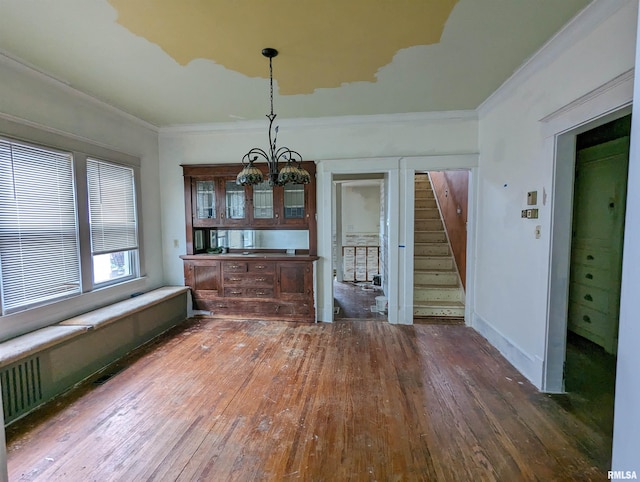 unfurnished dining area featuring dark hardwood / wood-style flooring, crown molding, and a notable chandelier