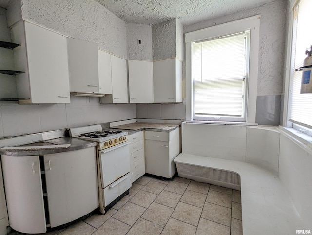 kitchen featuring white cabinets, white gas stove, and a healthy amount of sunlight