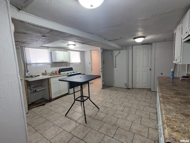 kitchen featuring gas range gas stove, sink, and white cabinetry