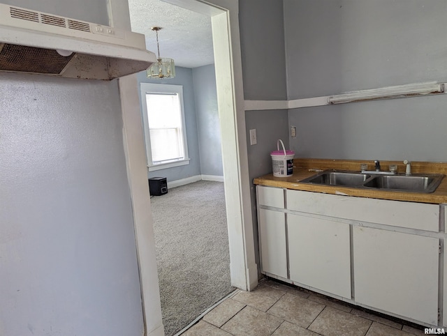 kitchen featuring light carpet, white cabinetry, a textured ceiling, pendant lighting, and sink