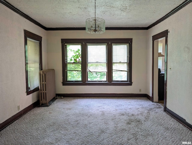 carpeted spare room with an inviting chandelier, radiator heating unit, a textured ceiling, and ornamental molding