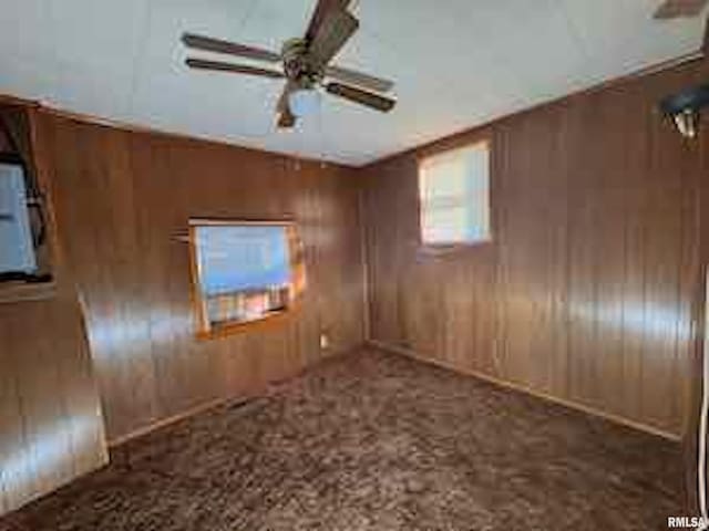 empty room with ceiling fan and wooden walls