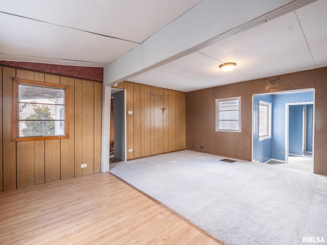 unfurnished room with beam ceiling and wooden walls