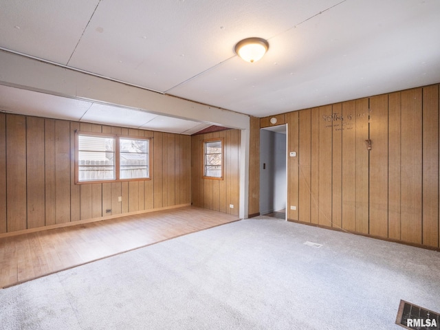 unfurnished room featuring light colored carpet and wood walls