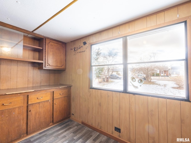 kitchen featuring built in desk, dark hardwood / wood-style floors, and wooden walls