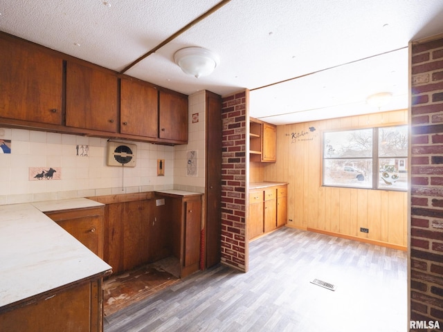 kitchen featuring a textured ceiling, wood walls, and light wood-type flooring