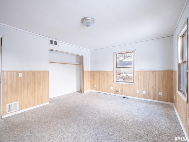 carpeted spare room with wood walls