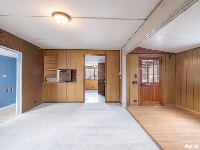 entrance foyer with lofted ceiling and wood walls