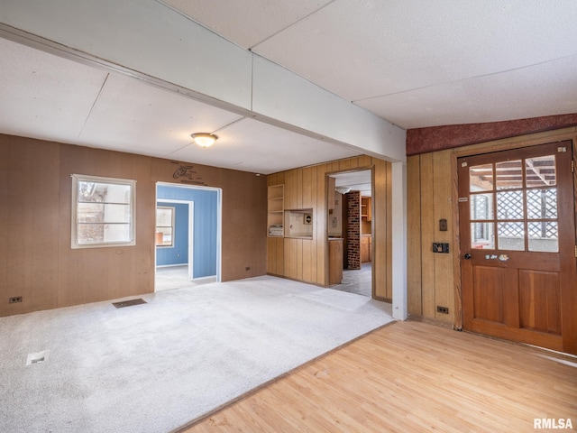 foyer entrance featuring light hardwood / wood-style flooring and wooden walls