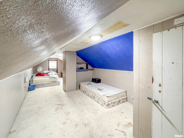 bedroom featuring a textured ceiling, carpet flooring, and vaulted ceiling