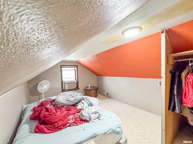 bedroom with a textured ceiling, lofted ceiling, and cooling unit