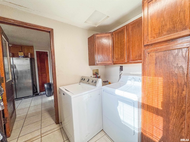 laundry area featuring light tile patterned flooring, washing machine and clothes dryer, and cabinets