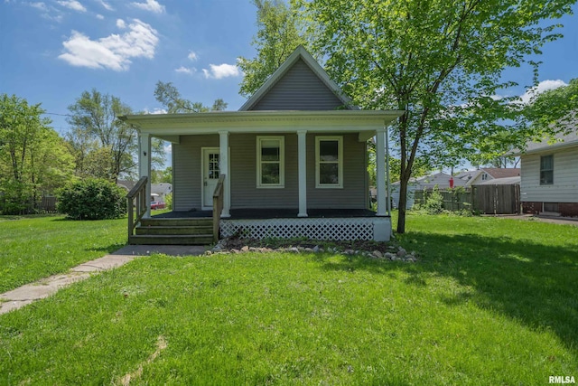 view of front of home featuring a porch, fence, and a front lawn