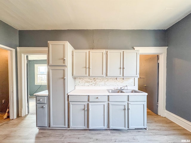 kitchen featuring sink, white cabinetry, light hardwood / wood-style flooring, and tasteful backsplash