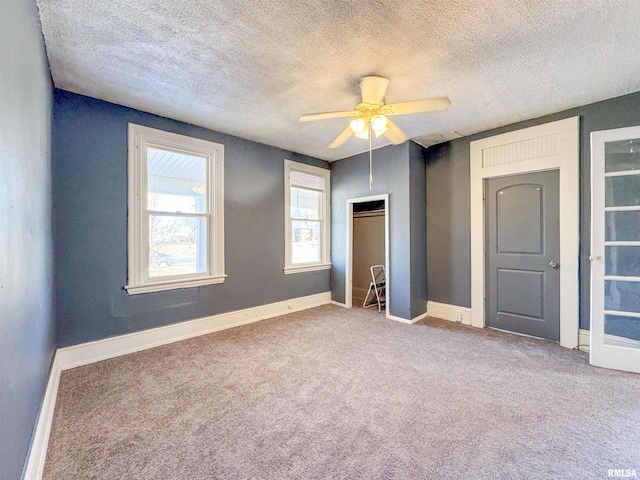 unfurnished bedroom with a textured ceiling, ceiling fan, and carpet