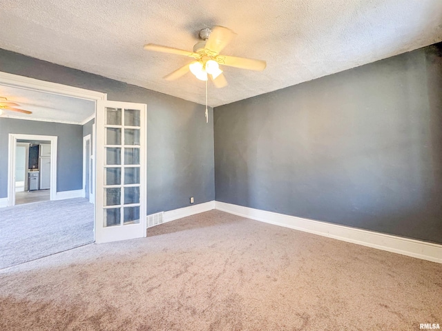 carpeted empty room with ceiling fan, a textured ceiling, and french doors