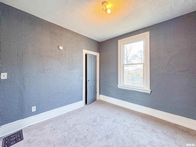 carpeted empty room featuring a textured ceiling