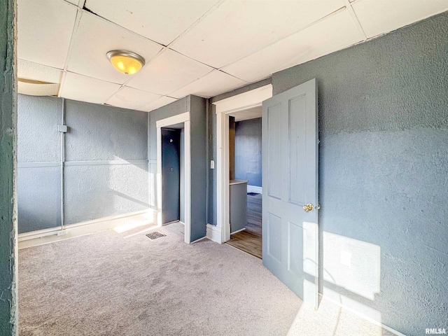 interior space featuring carpet flooring and a drop ceiling