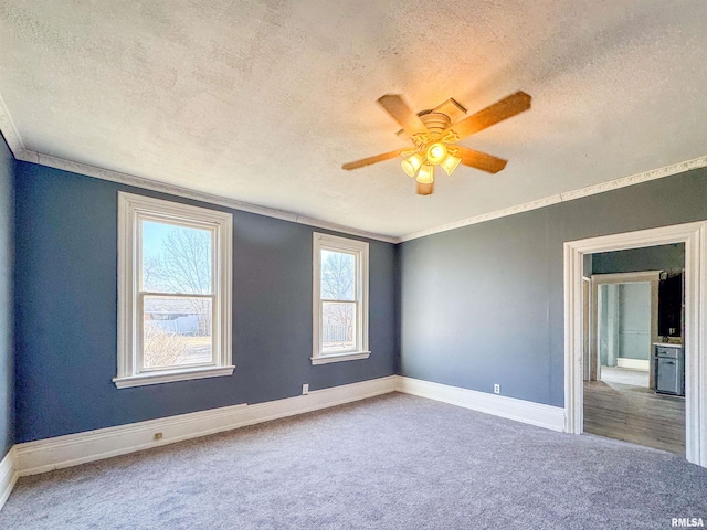 carpeted spare room featuring a textured ceiling, ceiling fan, and ornamental molding