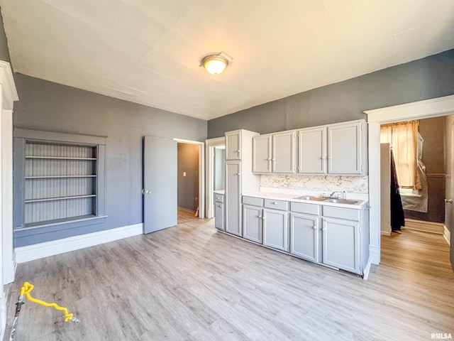 kitchen with light wood-type flooring, tasteful backsplash, and sink