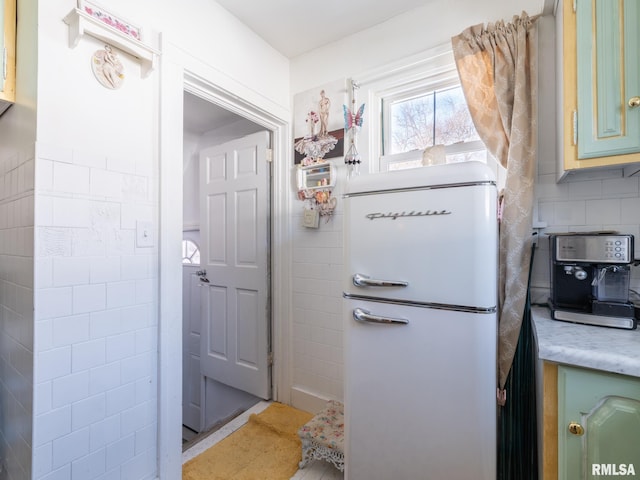 interior space featuring refrigerator, tasteful backsplash, and green cabinetry