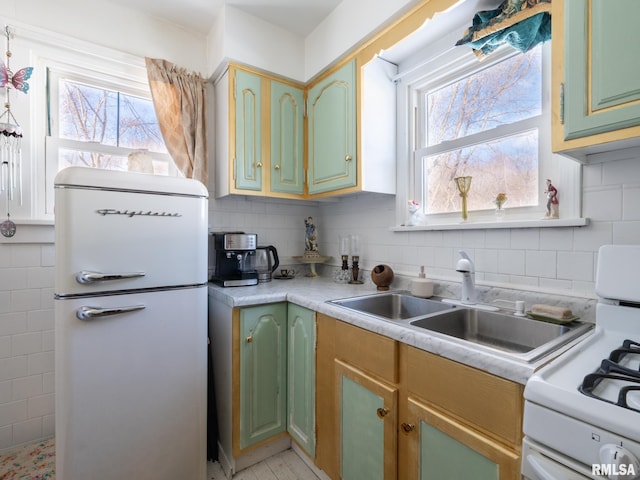 kitchen with sink, white appliances, backsplash, and green cabinetry