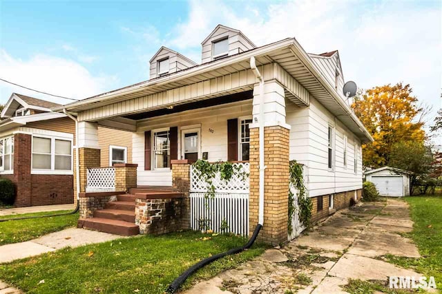 view of front of home featuring a front yard, covered porch, a garage, and a storage unit