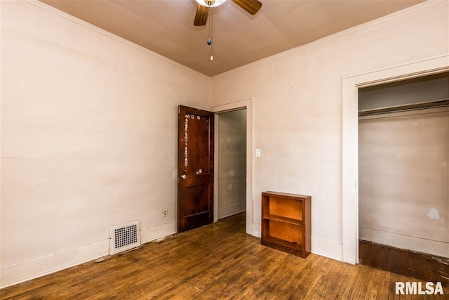 unfurnished bedroom with crown molding, dark wood-type flooring, a closet, and ceiling fan