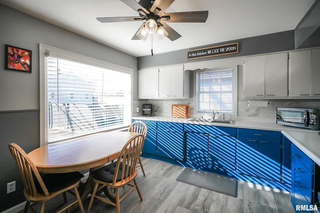 kitchen featuring decorative backsplash, sink, blue cabinetry, and white cabinetry