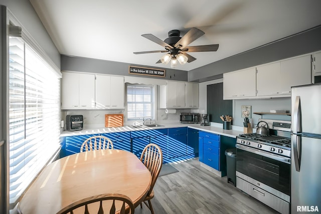 kitchen featuring light wood-type flooring, blue cabinetry, stainless steel appliances, and white cabinetry