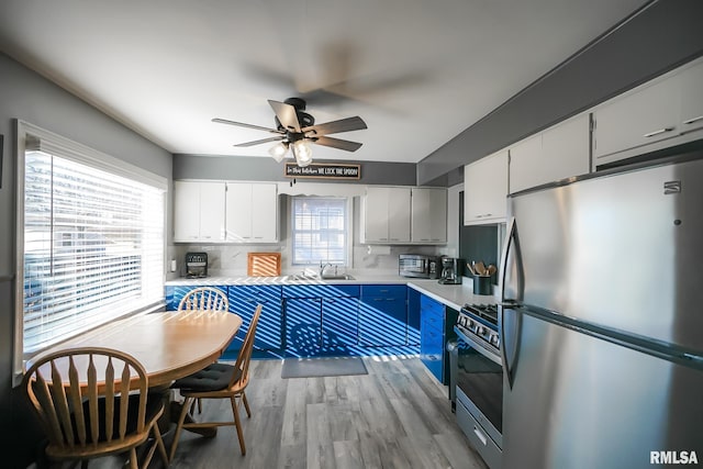 kitchen featuring white cabinets, stainless steel appliances, light hardwood / wood-style floors, sink, and ceiling fan