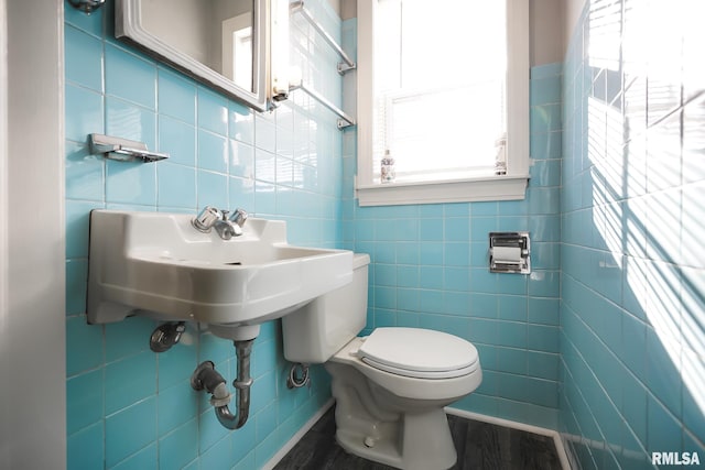 bathroom with toilet, hardwood / wood-style flooring, decorative backsplash, tile walls, and sink