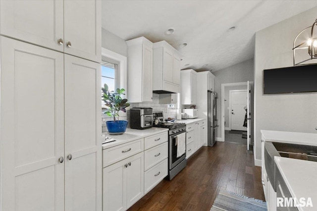 kitchen featuring appliances with stainless steel finishes, backsplash, dark wood-type flooring, vaulted ceiling, and white cabinets