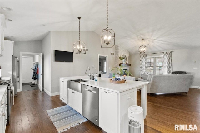 kitchen with lofted ceiling, decorative light fixtures, white cabinetry, stainless steel appliances, and a center island with sink