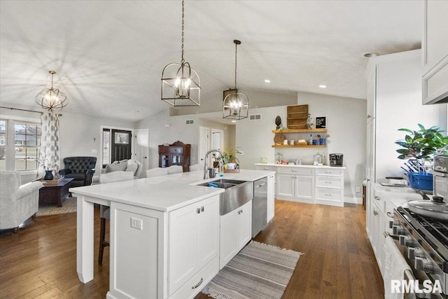 kitchen featuring appliances with stainless steel finishes, white cabinetry, lofted ceiling, and a kitchen island with sink