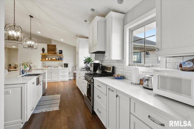 kitchen with white cabinets, appliances with stainless steel finishes, decorative light fixtures, decorative backsplash, and vaulted ceiling