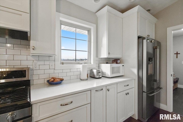 kitchen with wall oven, white cabinets, stainless steel fridge, and backsplash