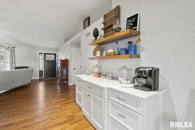 bar featuring light hardwood / wood-style floors and white cabinets