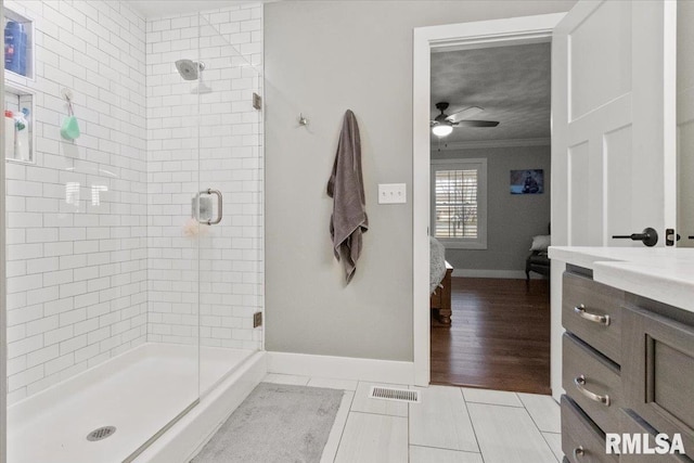 bathroom featuring ceiling fan, vanity, tile patterned floors, ornamental molding, and an enclosed shower